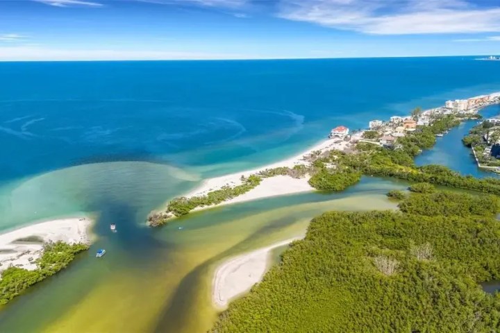 Aerial view of a coastal area with beaches, blue sea, and lush green vegetation.