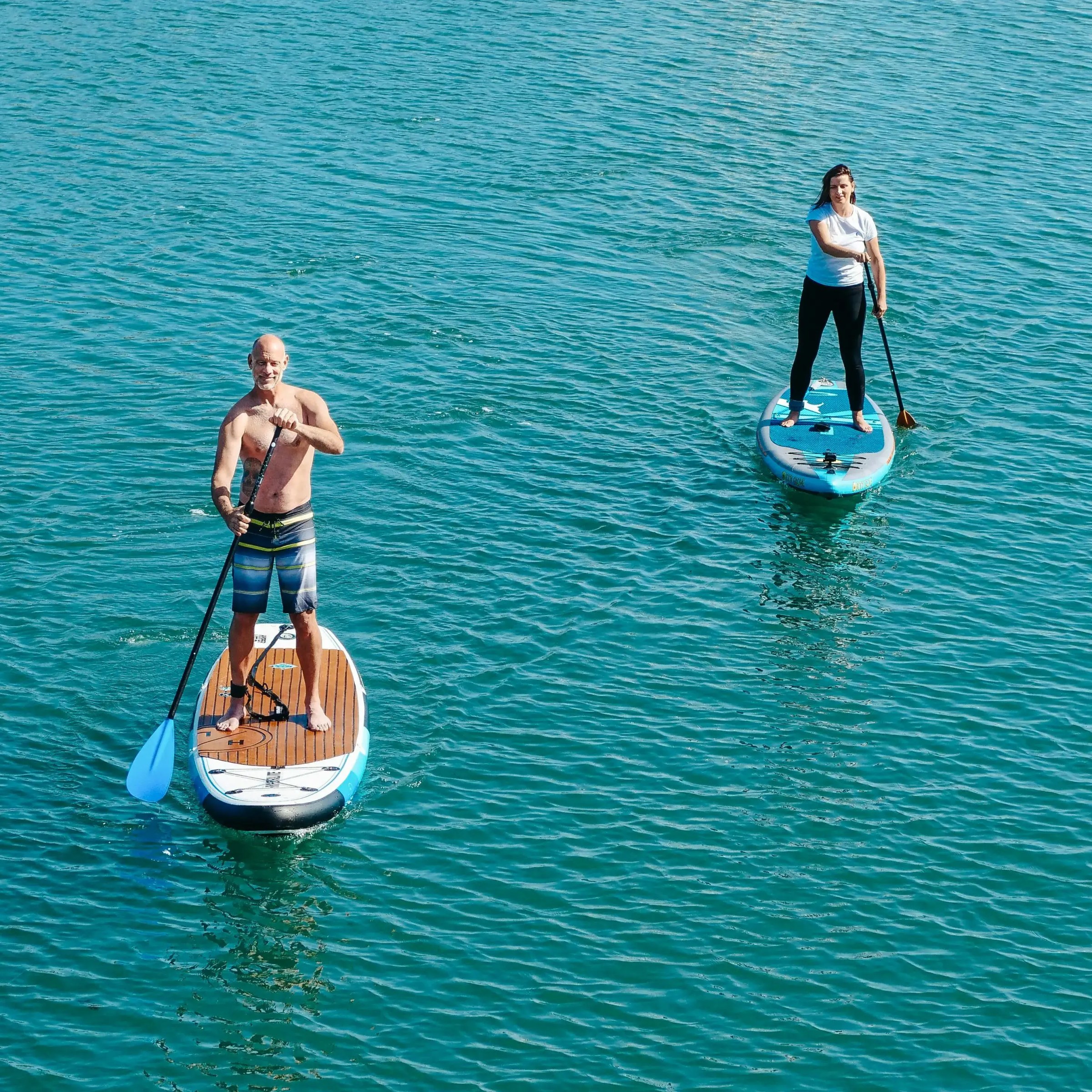 Two people paddleboarding on calm blue water.