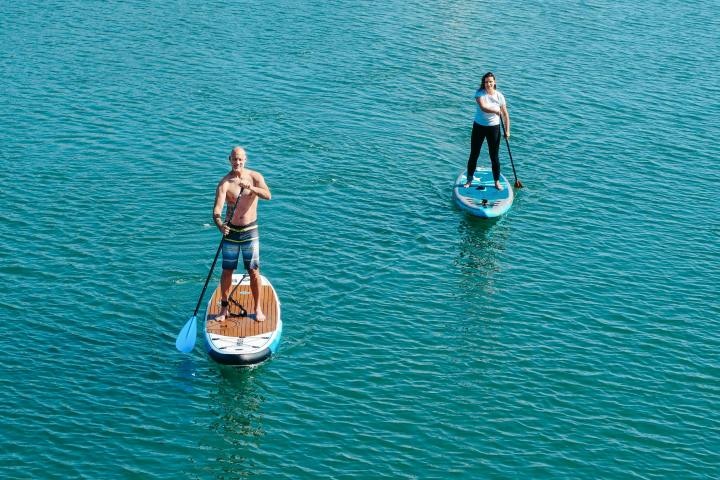 Two people paddleboarding on a calm blue lake.