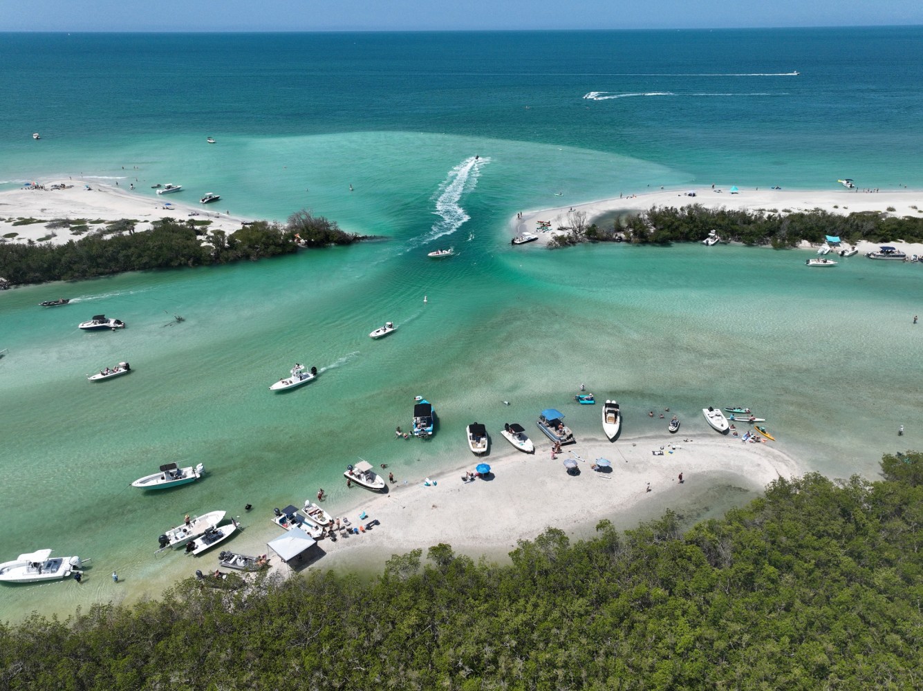 Aerial view of boats anchored at a tropical inlet with turquoise water.